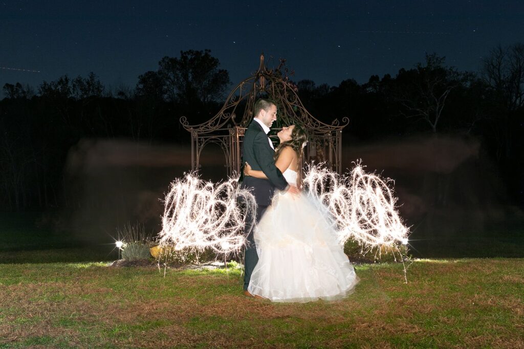 Nighttime portrait of bride and groom with sparkler light trail surrounding them
